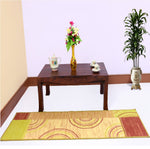 A solid wood coffee table in a mahogany finish positioned on a patterned rug, with a vase of flowers and a tea set on top.