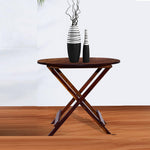 A solid wood folding coffee table in a provincial finish placed on a wooden floor, with decorative vases on top.