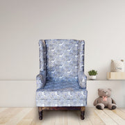 A wooden single seater sofa chair with blue upholstered padding, placed in a room with minimal decor, next to a small shelf with a plant and a teddy bear.