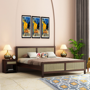 A wooden king-size bed with a brown finish, featuring a headboard with a woven design, placed in a bedroom setting with two side tables, lamps, and decorative wall art above the bed.