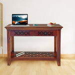 Wooden desk with a laptop, plant, and decorative items in a room.