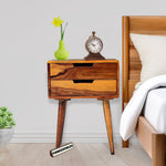 Wooden nightstand with decorative items next to a bed in a bedroom setting.
