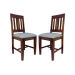 A pair of wooden dining chairs with a teak finish and padded seats in a room setting.