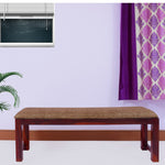 A solid wood dining bench with a maple finish, upholstered with fabric in a living room setting.