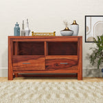 A wooden sideboard cabinet with two drawers and open shelves, placed in a living room setting with decorative items on top.