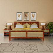 Wooden bed with checkered bedspread in a bedroom setting with lamps and wall art.