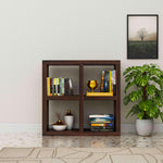 Wooden bookshelf with books and decor items against a light wall with a plant.