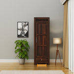 Wooden cabinet in a room with a plant, lamp, and framed picture on the wall.