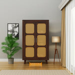 Wooden cabinet with wicker doors in a room with a lamp and plant.