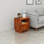 Wooden side table with decorative items next to a gray sofa in a living room.