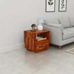 Wooden side table with decorative items next to a gray sofa in a living room.