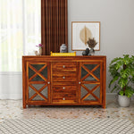 Wooden sideboard with decorative items in a room with curtains and a plant.
