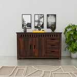 Wooden sideboard with decorative items in a room with a plant and framed pictures on the wall.