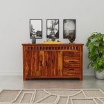 Wooden sideboard with decorative items in a room with a plant and framed pictures on the wall.