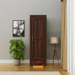 Wooden wardrobe in a room with a plant, lamp, and framed picture on the wall.