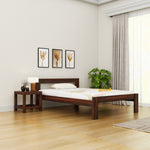 Wooden bed in a room with a side table, lamp, and decor items.