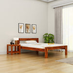 Wooden bed in a bedroom with a side table, lamp, and decor items.