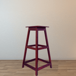 Wooden bar stool against a plain wall