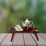 Tea set with teapot and cups on a wooden tray with flowers against a blurred green background