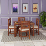 Wooden dining set with four chairs in a room with purple walls and framed pictures.
