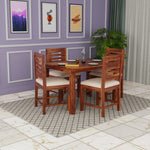 Wooden dining set with four chairs in a room with purple walls and framed pictures.
