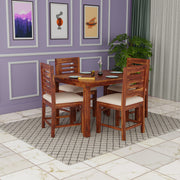 Wooden dining set with four chairs in a room with purple walls and framed pictures.