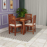 Wooden dining set with four chairs in a room with purple walls and a plant.
