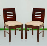 Two wooden dining chairs with beige upholstered seat cushions, viewed from a slight angle against a neutral background.