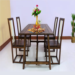 A solid wood dining table with four chairs arranged around it in a dining room setting. The table is rectangular, and the chairs are matching with a simple design.