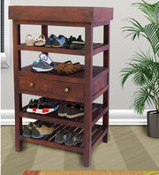 A wooden shoe rack with two drawers, multiple shelves with shoes on them, placed against a wall with a potted plant beside it.