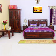 A wooden queen size bed with storage, featuring a brown finish. The bed is accompanied by side tables, a headboard, footboard, and is set in a room with a painting above the bed, a window with curtains, and decorative items on the surfaces.