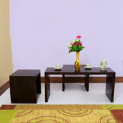 A wooden coffee table with stools in a mahogany finish, placed in a living room setting with decorative items on top.