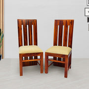 A pair of wooden dining chairs with a honey finish, featuring a contoured seat and vertical back slats.