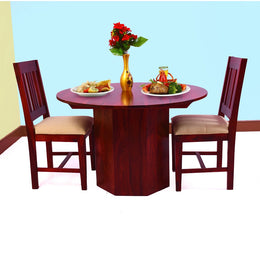 A wooden dining table with two chairs, set against a plain background. The table is circular with a red-brown finish, and the chairs are straight-back with a beige seat pad.