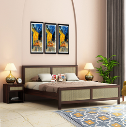 A wooden king-size bed with a brown finish, featuring a headboard with a woven design, placed in a bedroom setting with two side tables, lamps, and decorative wall art above the bed.