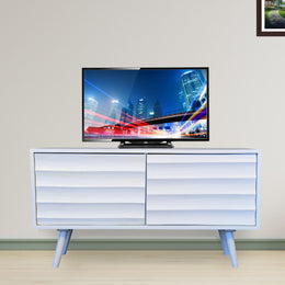 A white finish mango wood TV cabinet with two doors, placed on a floor and against a wall, with a flat-screen TV on top.