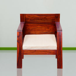 A wooden single seater sofa with a beige cushion, placed against a neutral background.