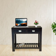 Black desk with a laptop and flowers in a room with a plant