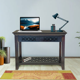 Laptop on a wooden desk with a lamp and plants in a room.