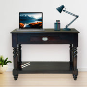 Dark wooden desk with a laptop, lamp, and decorative items on a light wood floor.