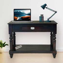 Dark wooden desk with a laptop, lamp, and decorative items on a light wood floor.