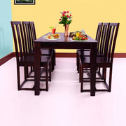 A solid wood dining table with six chairs arranged around it in a dining room setting. The table and chairs have a dark rosewood finish.