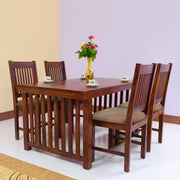 A wooden dining table set with four chairs, a square table, and a vase of flowers on top in a room with a light purple wall.