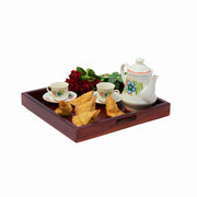 A wooden breakfast tray with a maple finish, including a teapot, cups, and a serving dish with snacks.