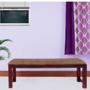 A solid wood dining bench with a maple finish, upholstered with fabric in a living room setting.