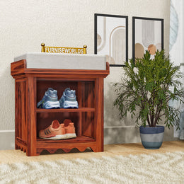 A wooden shoe rack with shelf storage placed in a living room setting, featuring pairs of shoes on the shelves.
