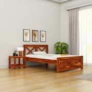 Wooden bed in a bedroom with a side table, lamp, and decor items.