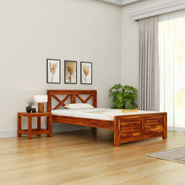 Wooden bed in a bedroom with a side table, lamp, and decor items.