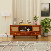 Wooden entertainment console with decorative items in a living room setting.