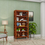 Wooden bookshelf with decorative items against a green wall in a room.
